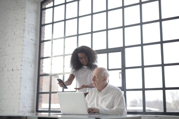 Multiracial businesspeople of different ages using gadgets while working together in creative workplace